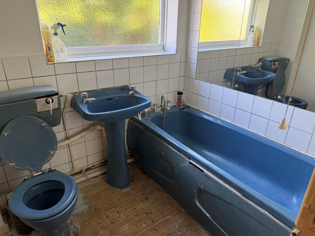Lot: 134 - TWO-BEDROOM FLAT WITH GARAGE IN NEED OF UPDATING - Blue bathroom suite with sink and WC